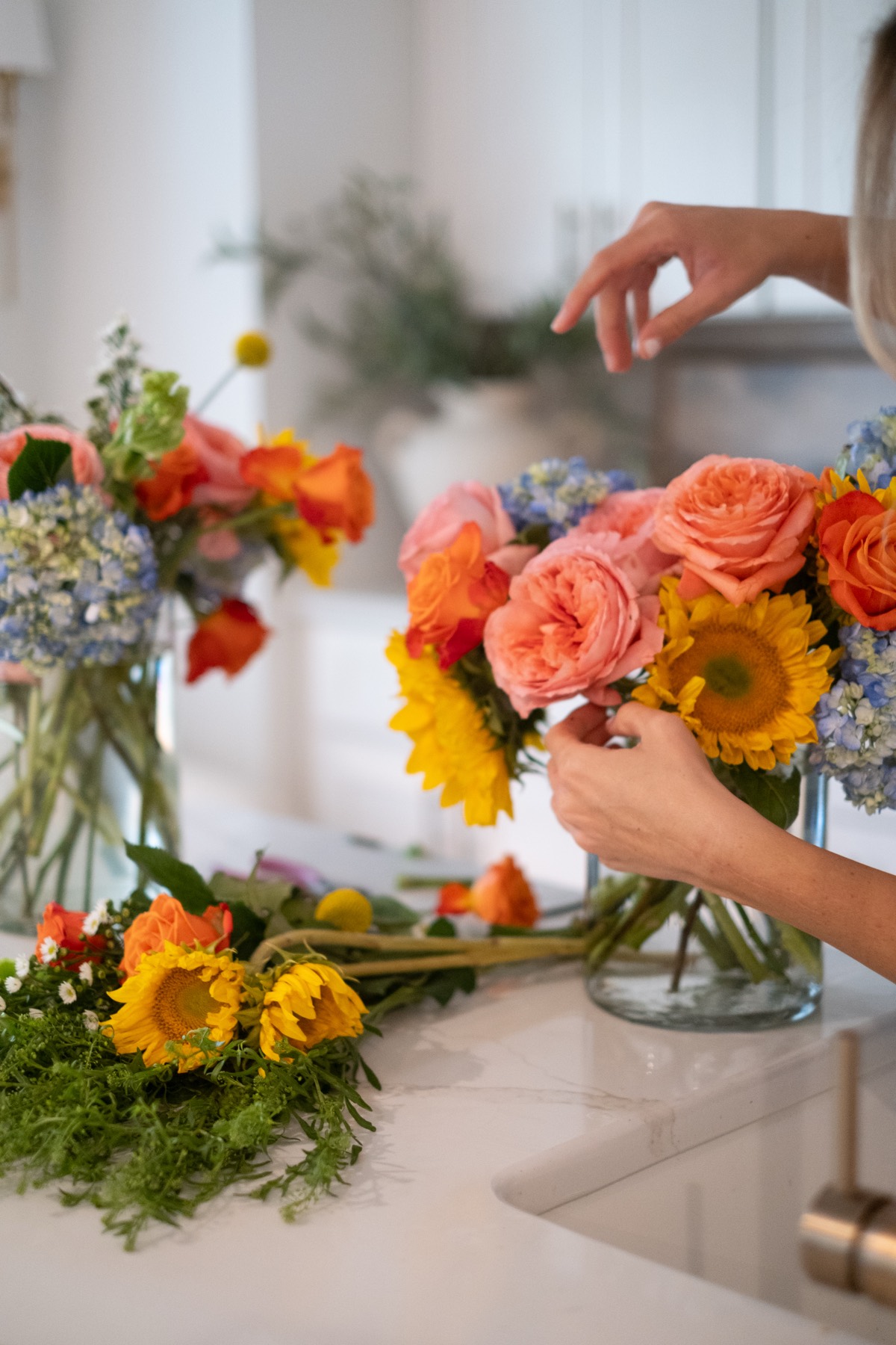 Hands arranging flowers on kitchen counter
