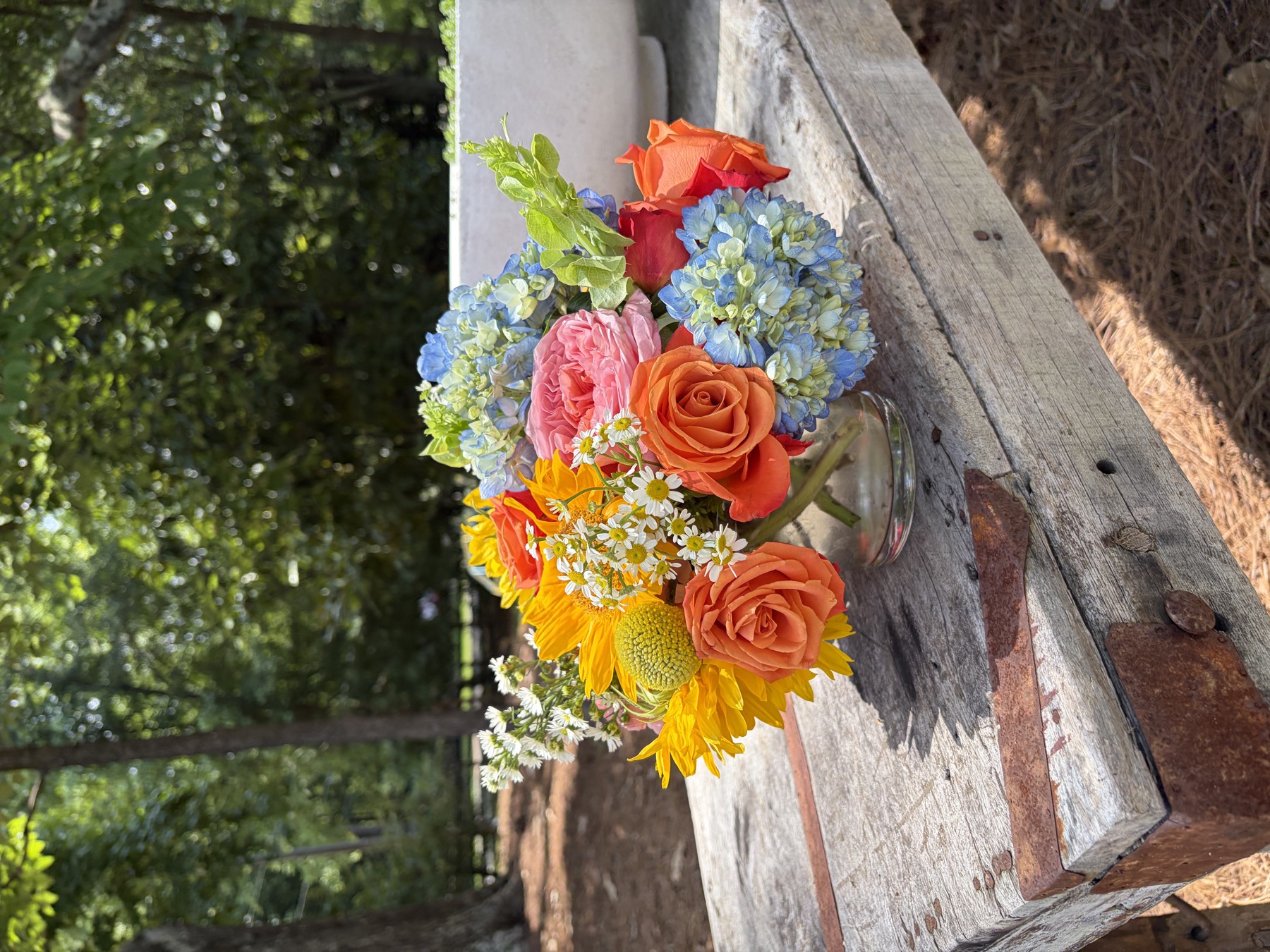 Colorful bouquet with orange roses and blue hydrangea on a wooden bench