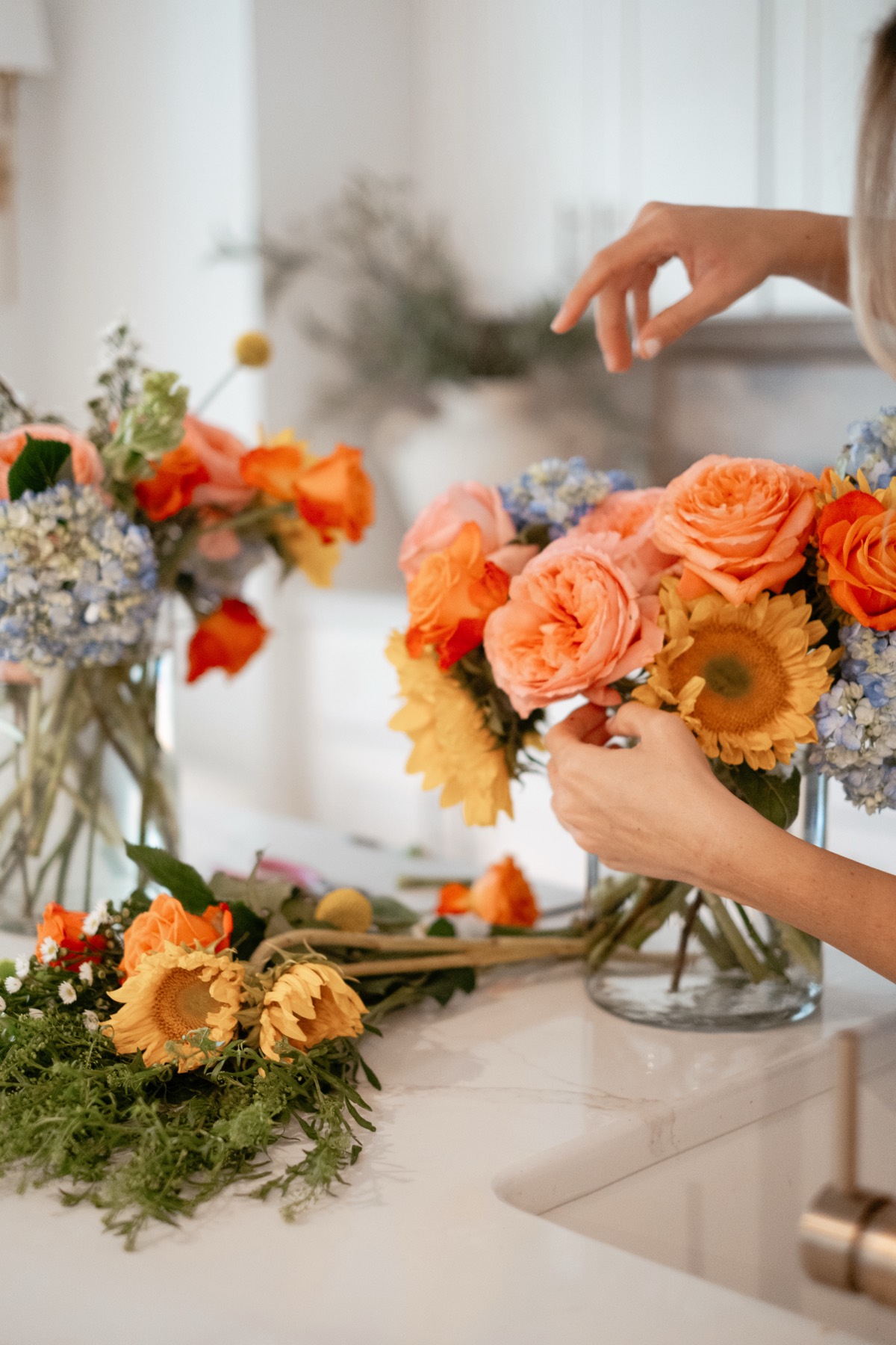 Hands arranging orange roses and gerbera daisies